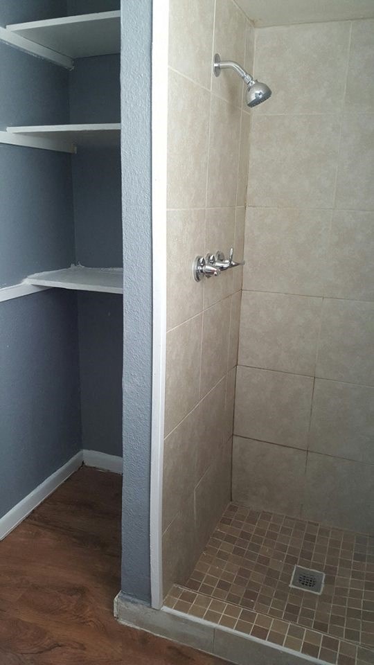 a bathroom with a shower and shelves in it