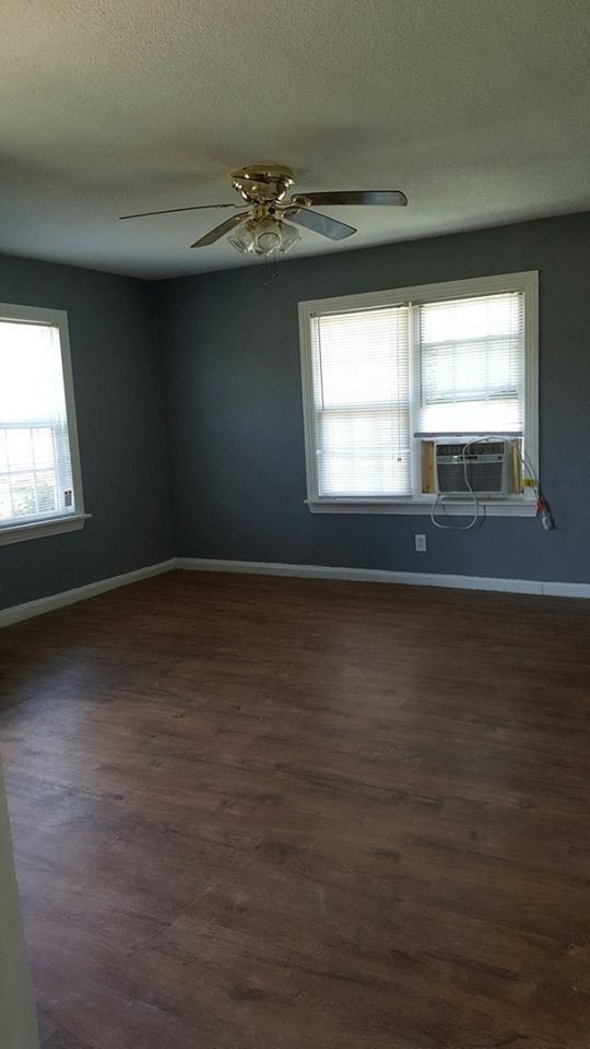 an empty room with a ceiling fan and two windows
