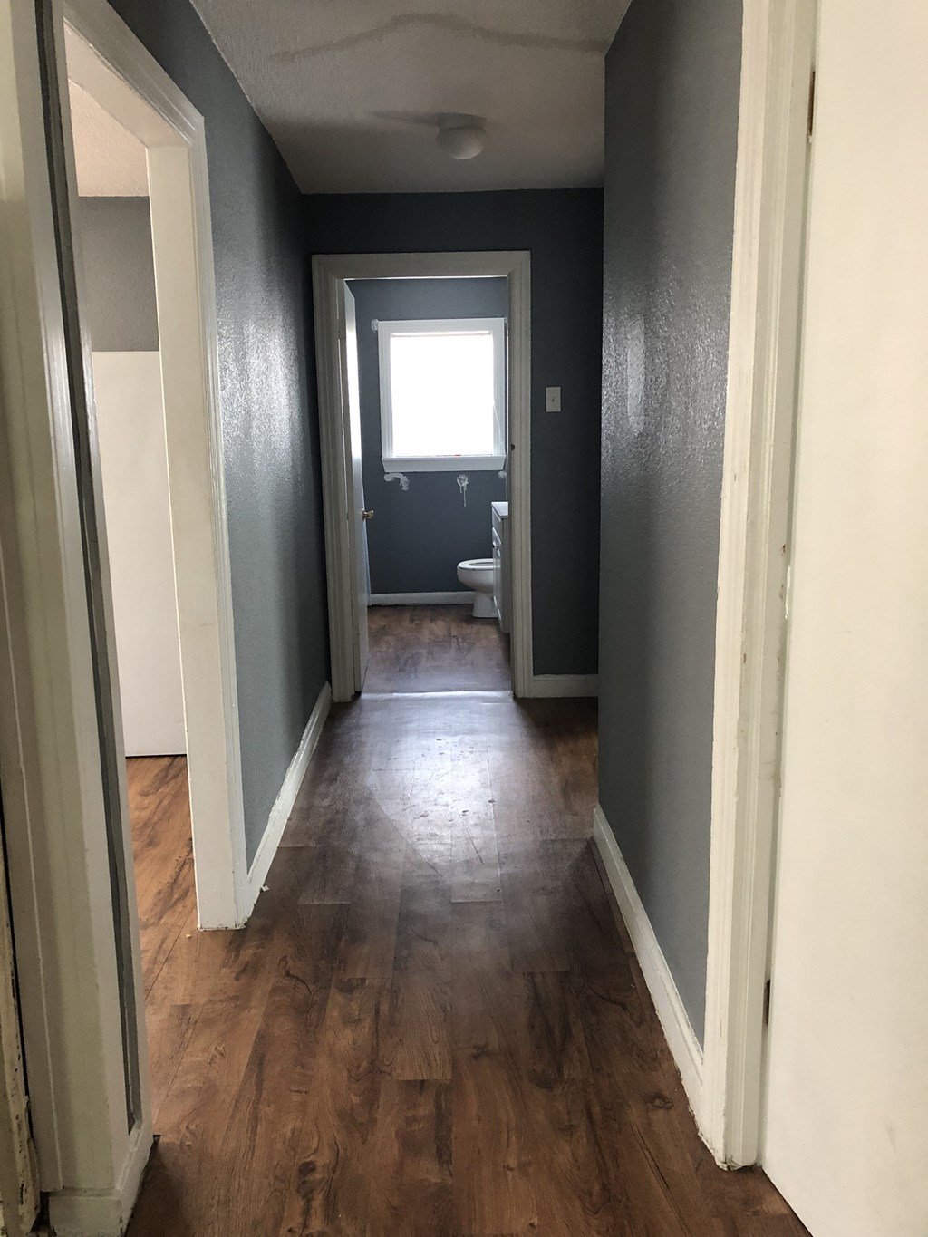 a hallway with a hard wood floor and a door to a bathroom