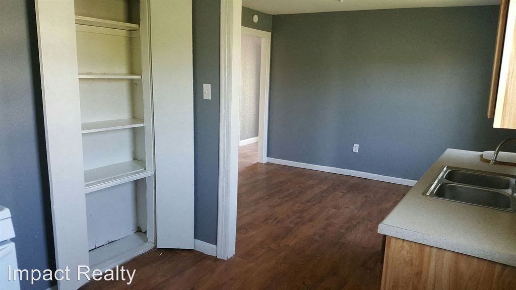 a kitchen and a living room with a sink and cabinets