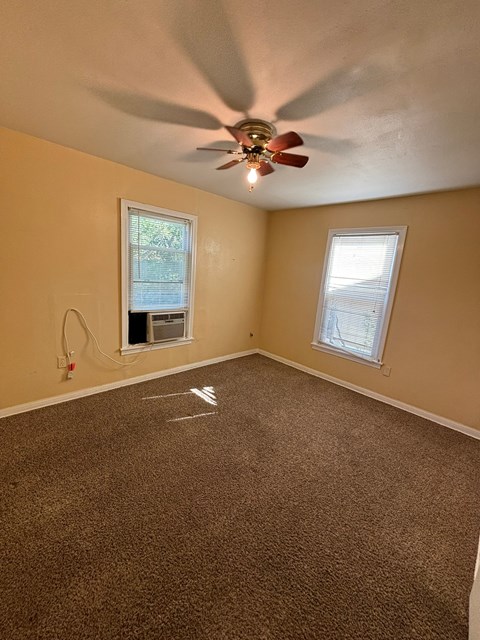 an empty living room with a ceiling fan and a window