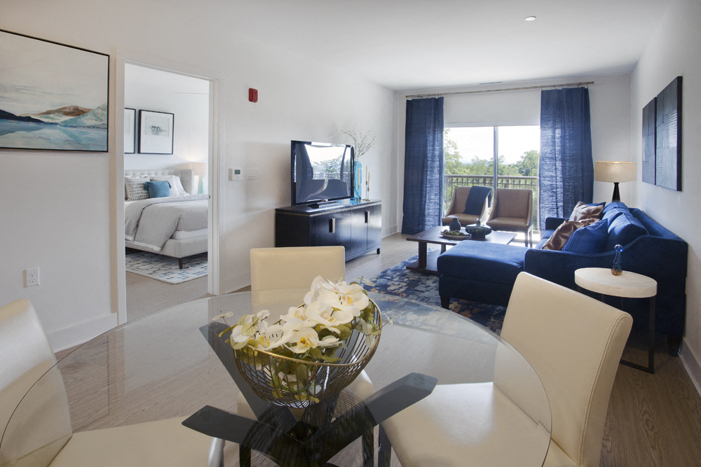 a living room with a glass table and a couch and a tv