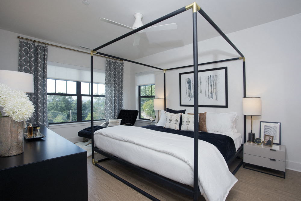 a bedroom with a large white bed and a black canopy bed