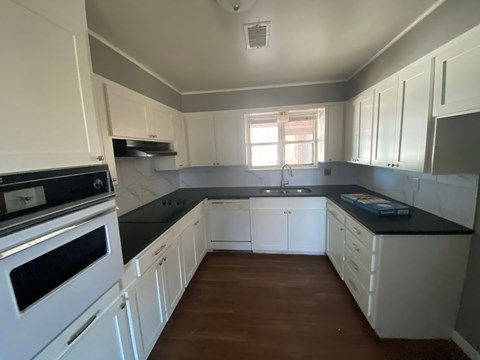 A kitchen with white cabinets and a black countertop.