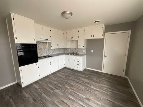 A kitchen with white cabinets and a black stove top oven.