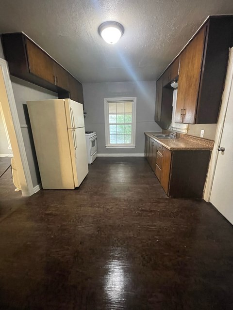 an empty kitchen with a refrigerator and a sink