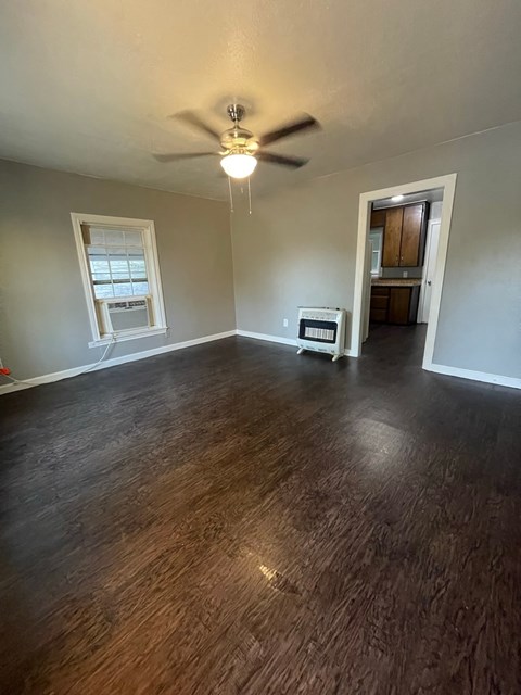 an empty living room with wood floors and a ceiling fan