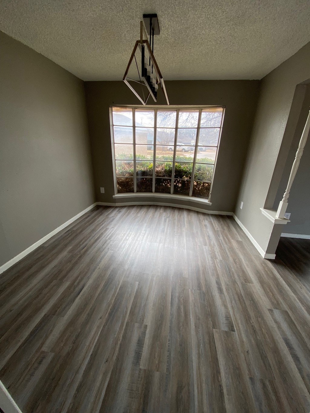 an empty living room with wood floors and a large window
