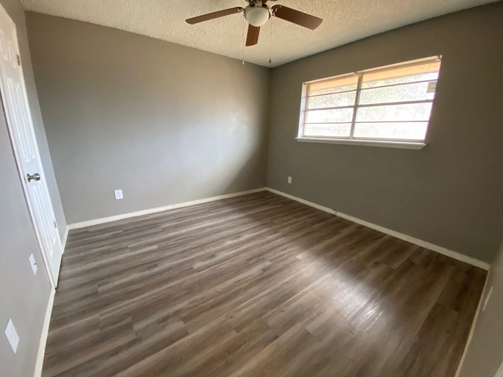 an empty living room with wood floors and a ceiling fan