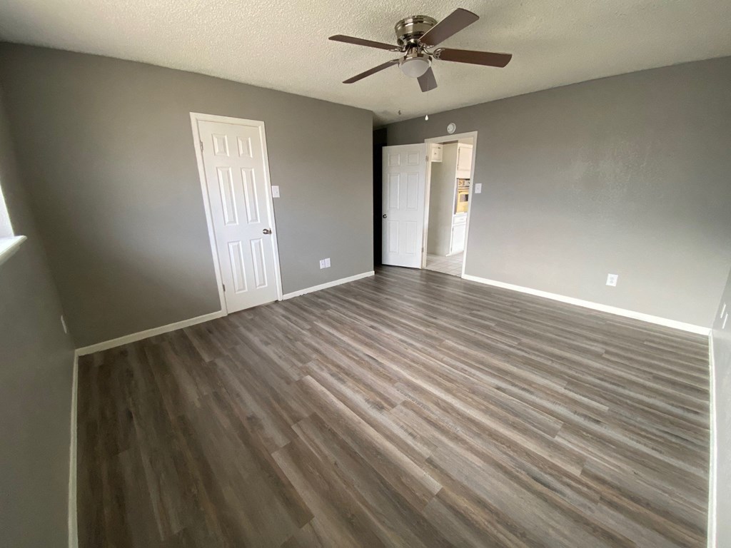 an empty living room with wooden floors and a ceiling fan
