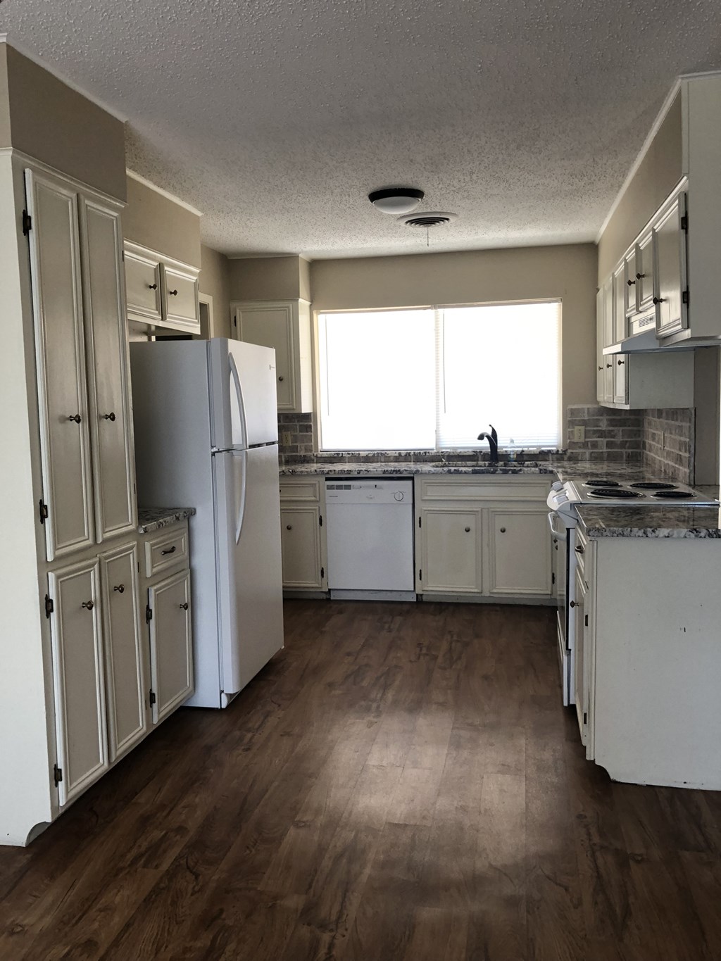 an empty kitchen with white cabinets and stainless steel appliances