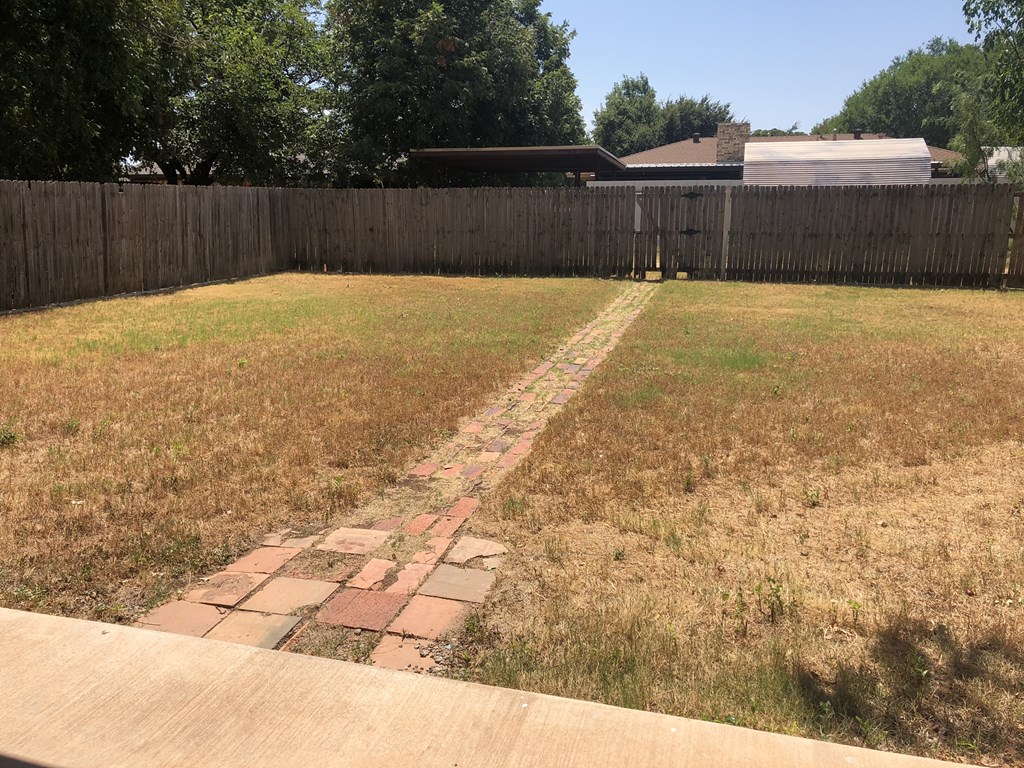 a backyard with a brick path in the grass