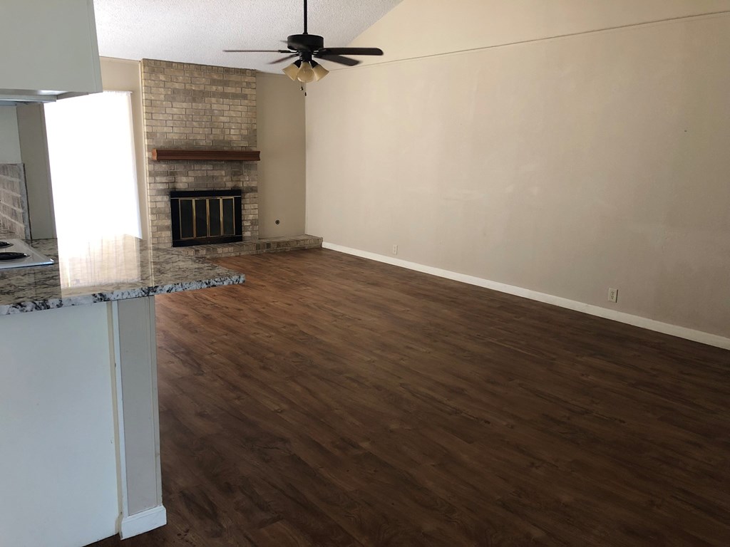 an empty living room with wood flooring and a fireplace