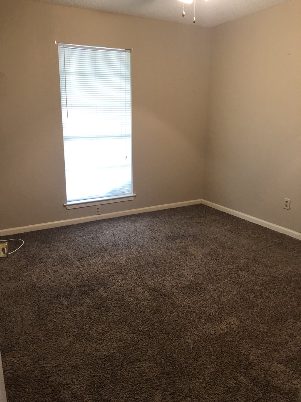 a room with a window and a carpeted floor