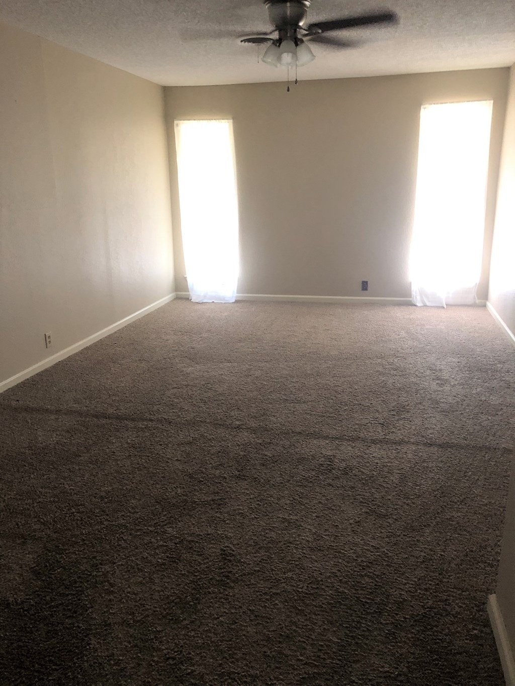 an empty living room with a ceiling fan
