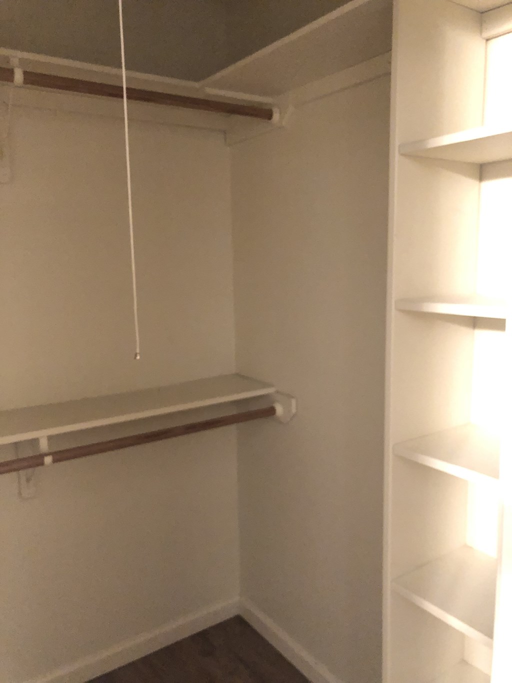a walk in closet with shelves and a hanging shelf