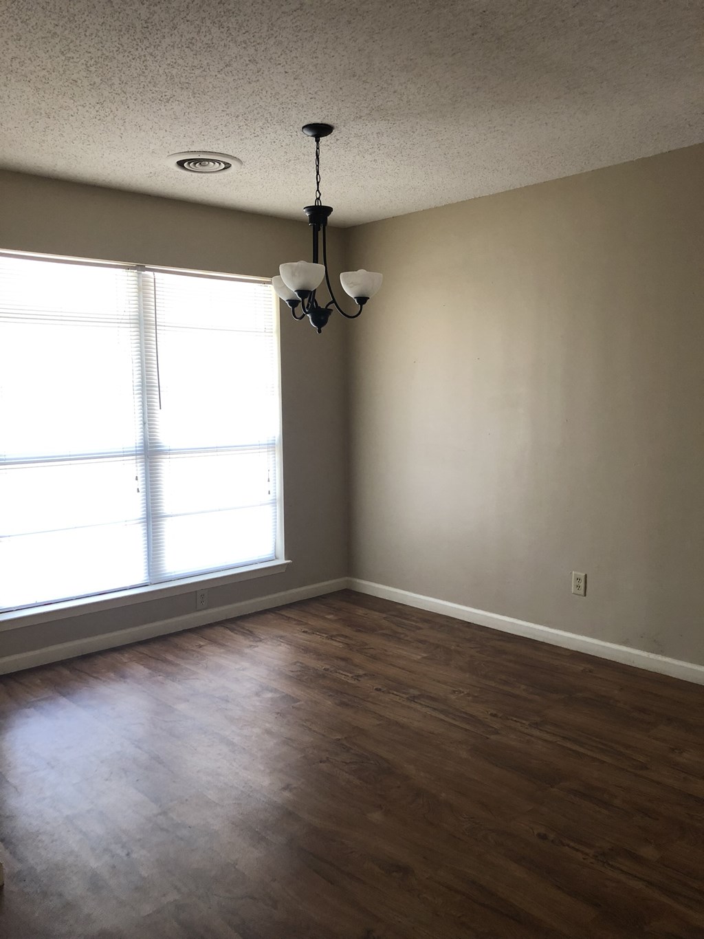 an empty living room with wood floors and a large window