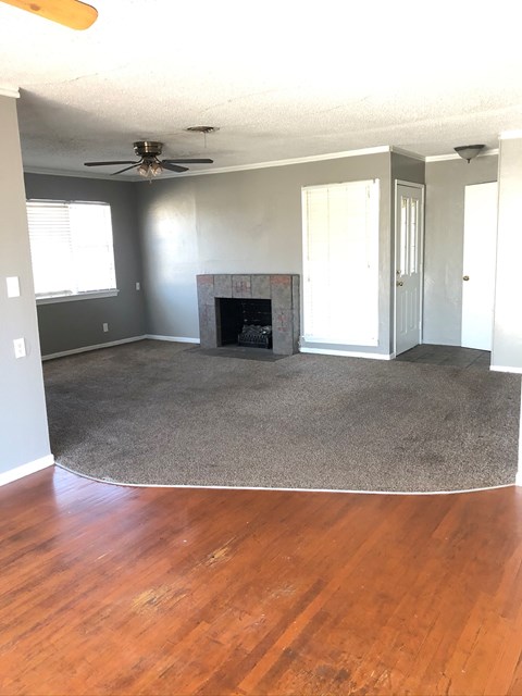 an empty living room with a rug and a fireplace