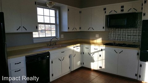 a kitchen with white cabinets and a sink and a window