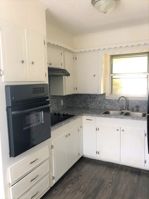 A kitchen with white cabinets and a black oven.