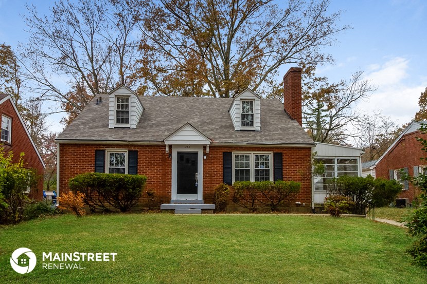 the front of a brick house with a lawn and a black door