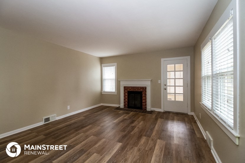 an empty living room with wood floors and a fireplace