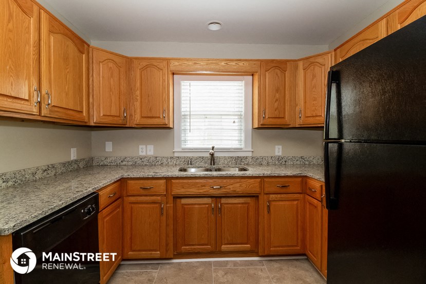 a kitchen with wooden cabinets and a black refrigerator