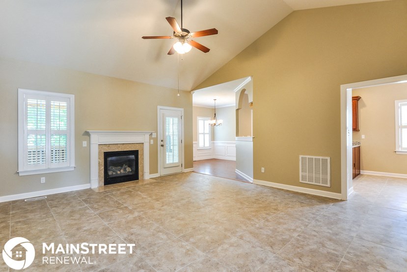 an empty living room with a fireplace and a ceiling fan