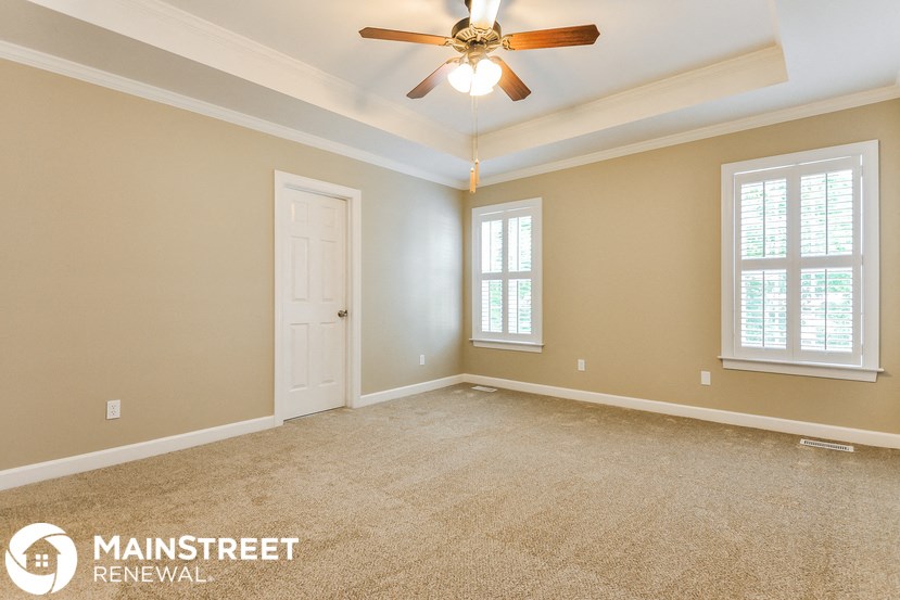 a empty living room with a ceiling fan and a white door