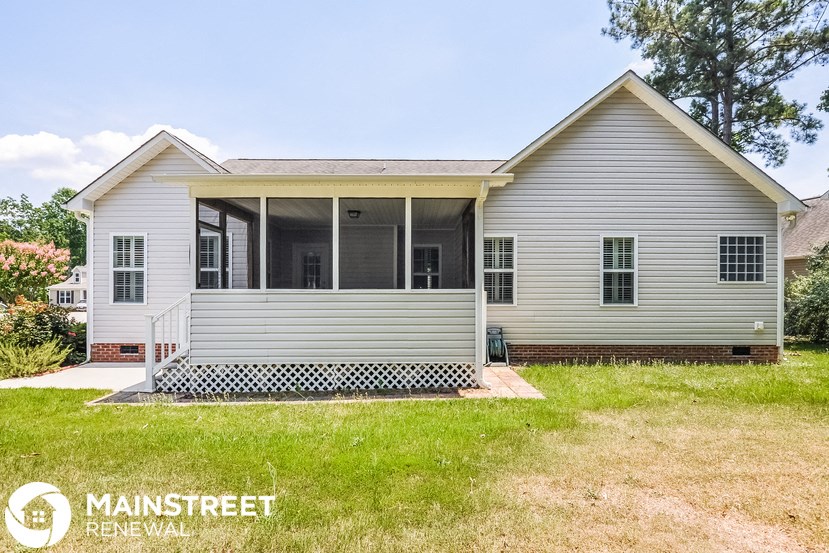 a white house with a covered porch and a lawn