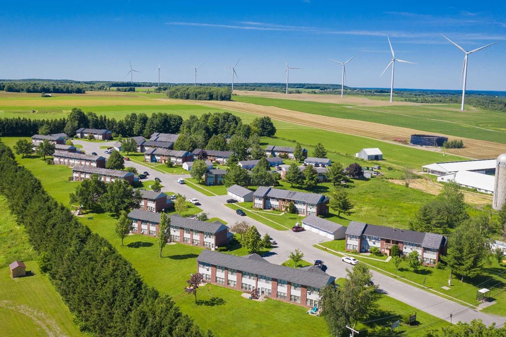 an aerial view of a village with wind turbines in the background
