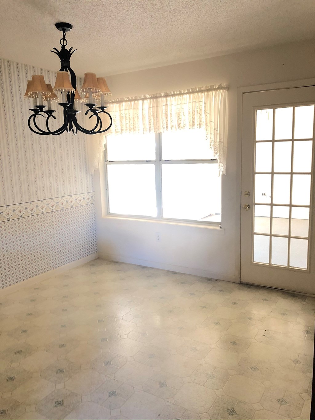 an empty room with a window and a chandelier