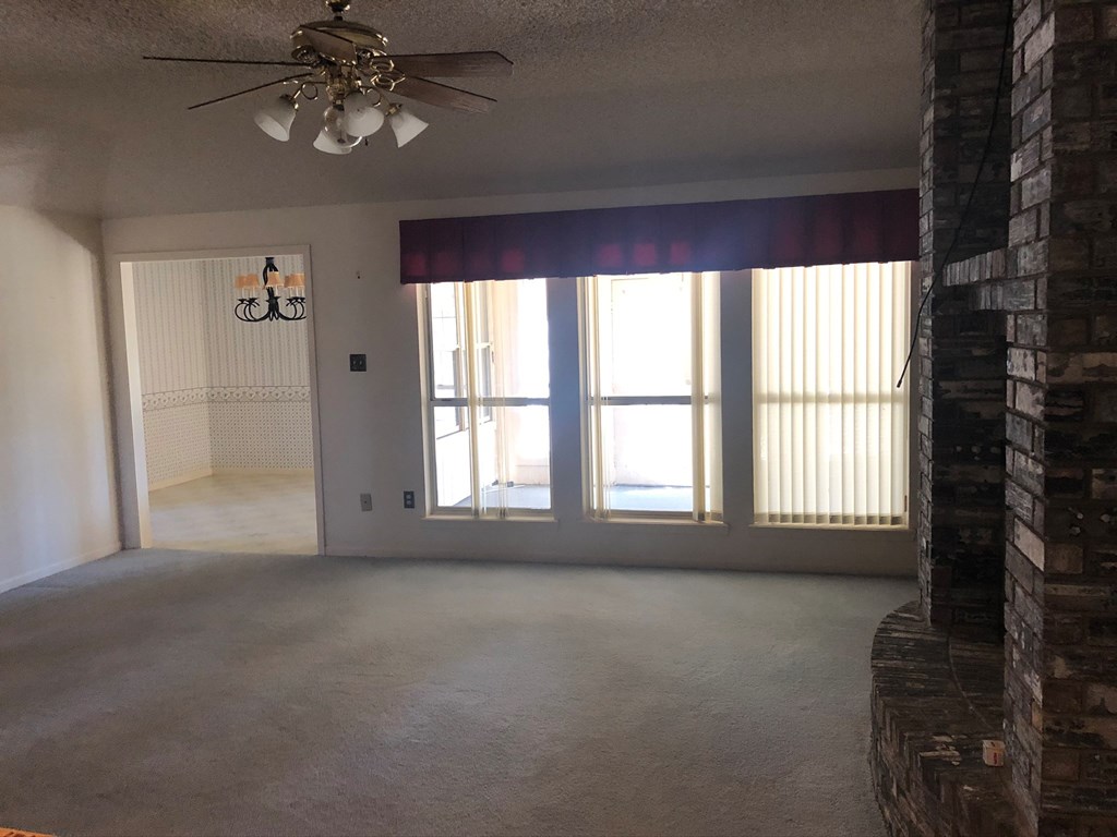 an empty living room with windows and a ceiling fan