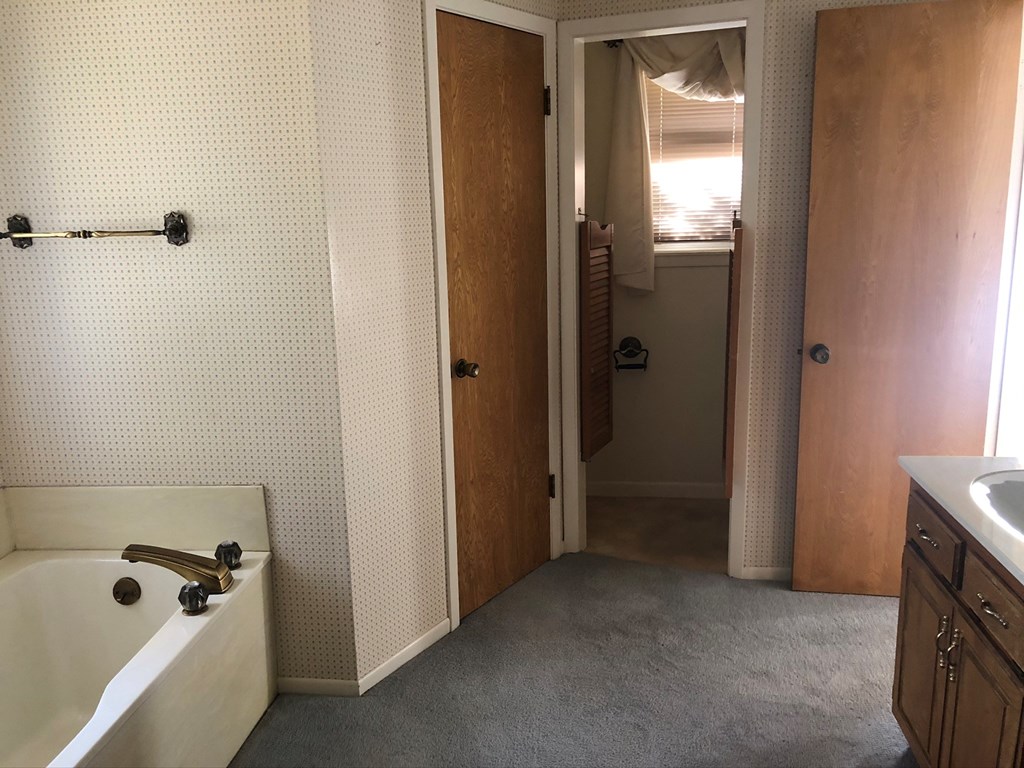 a bathroom with a sink and a bath tub and a doorway to a bedroom