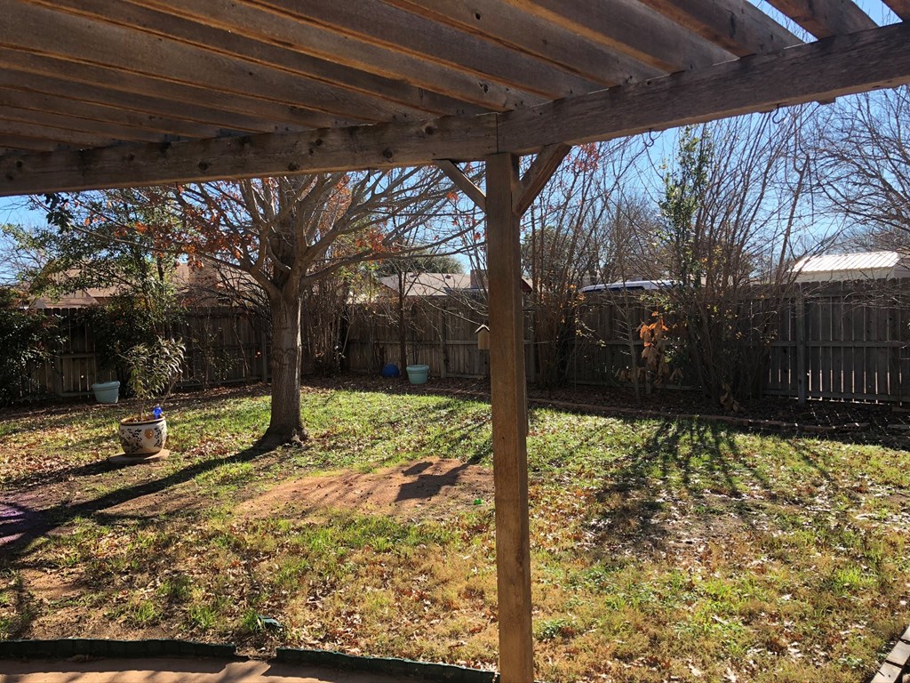 the backyard of a home with a wooden roof and a yard with trees