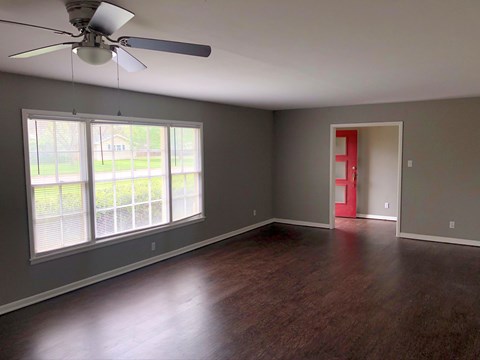 A room with a ceiling fan and sliding glass doors.