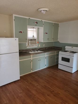an empty kitchen with green cabinets and white appliances