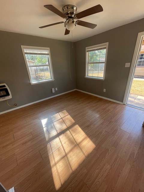 an empty living room with wooden floors and a ceiling fan