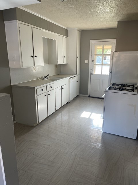an empty kitchen with white cabinets and stainless steel appliances