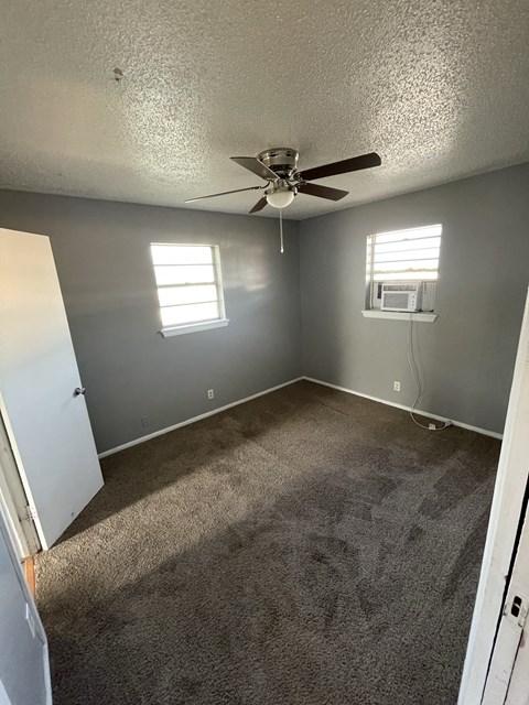 an empty room with carpet and a ceiling fan