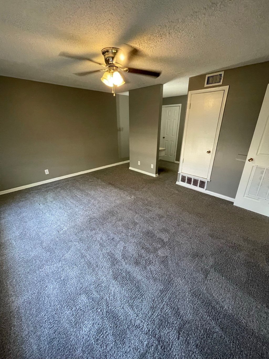 an empty living room with carpet and a ceiling fan