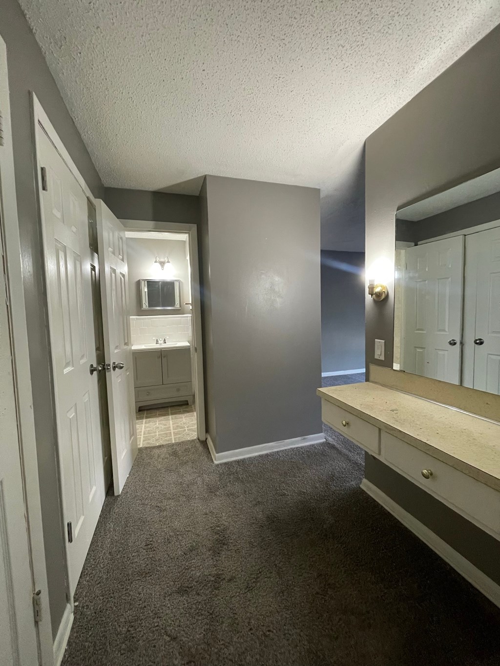 a bathroom with a sink and a mirror and a hall way with a closet