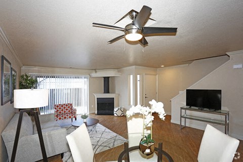 A living room with a grey couch and a white ceiling fan.