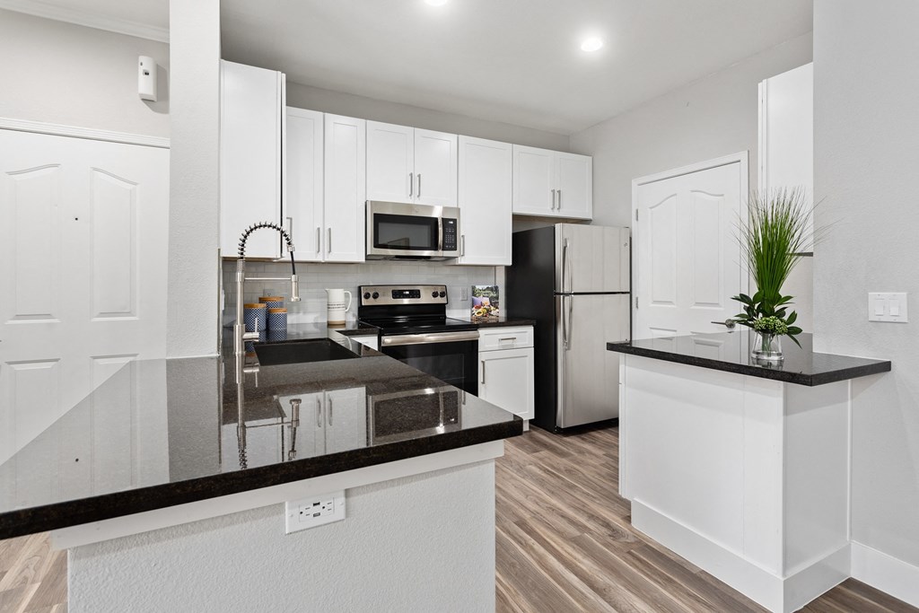 a kitchen with white cabinets and black counter tops