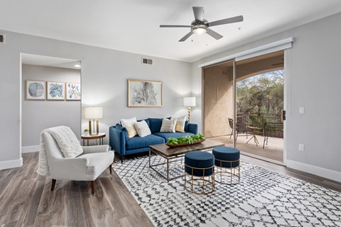 a living room with a blue couch and chairs and a ceiling fan