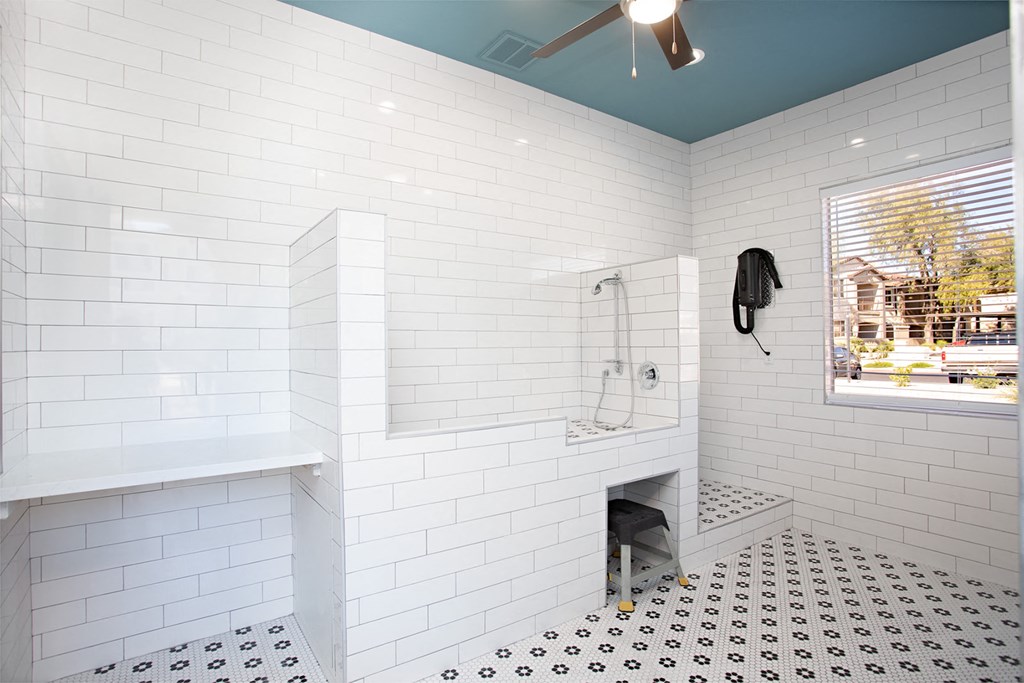 a white tiled bathroom with a shower and a window