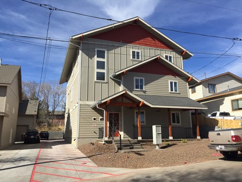 a gray house with a red roof and a driveway