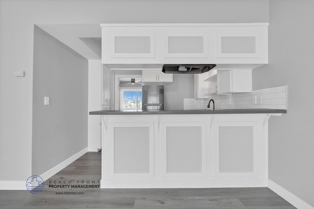 a white kitchen with white cabinets and a black counter top