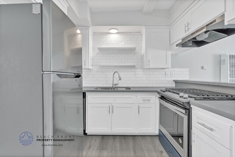 an updated kitchen with white cabinets and stainless steel appliances