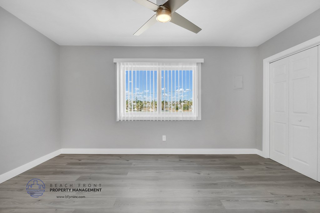 the living room of a rental house with a window and a ceiling fan